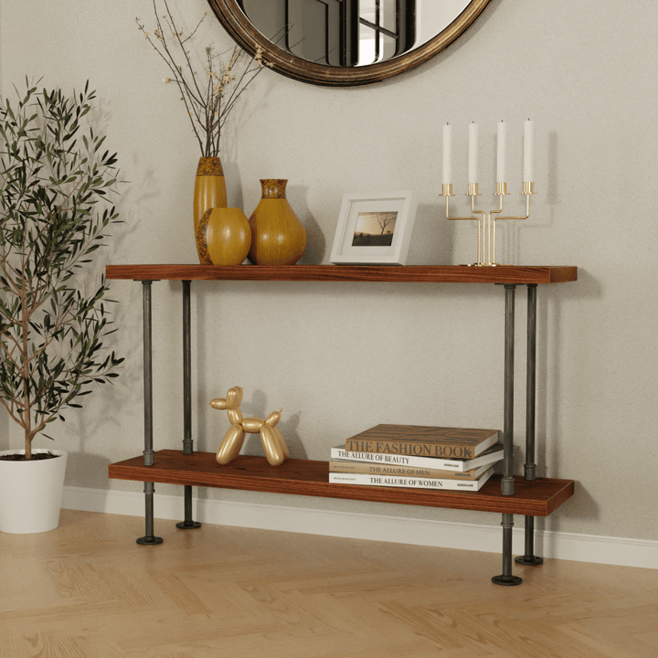 A chic console table displaying a balanced mix of decor, including vases, a candlestick, books, and a metallic dog sculpture, under a round mirror, next to a potted plant, enhancing a modern home interior.