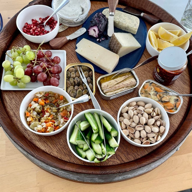 Enjoy a gourmet wooden platter featuring an array of cheeses, fresh grapes, cucumber slices, mixed nuts, and savory dips—a perfect setup for social gatherings or a luxurious snack spread. #CheeseBoard #SnackPlatter #Foodie #Entertaining