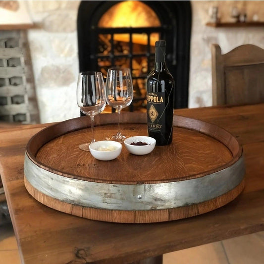 Cozy wine setup with a bottle and glasses on a wooden barrel, accompanied by snacks, against the backdrop of a warm fireplace. Ideal for relaxed evenings at home.