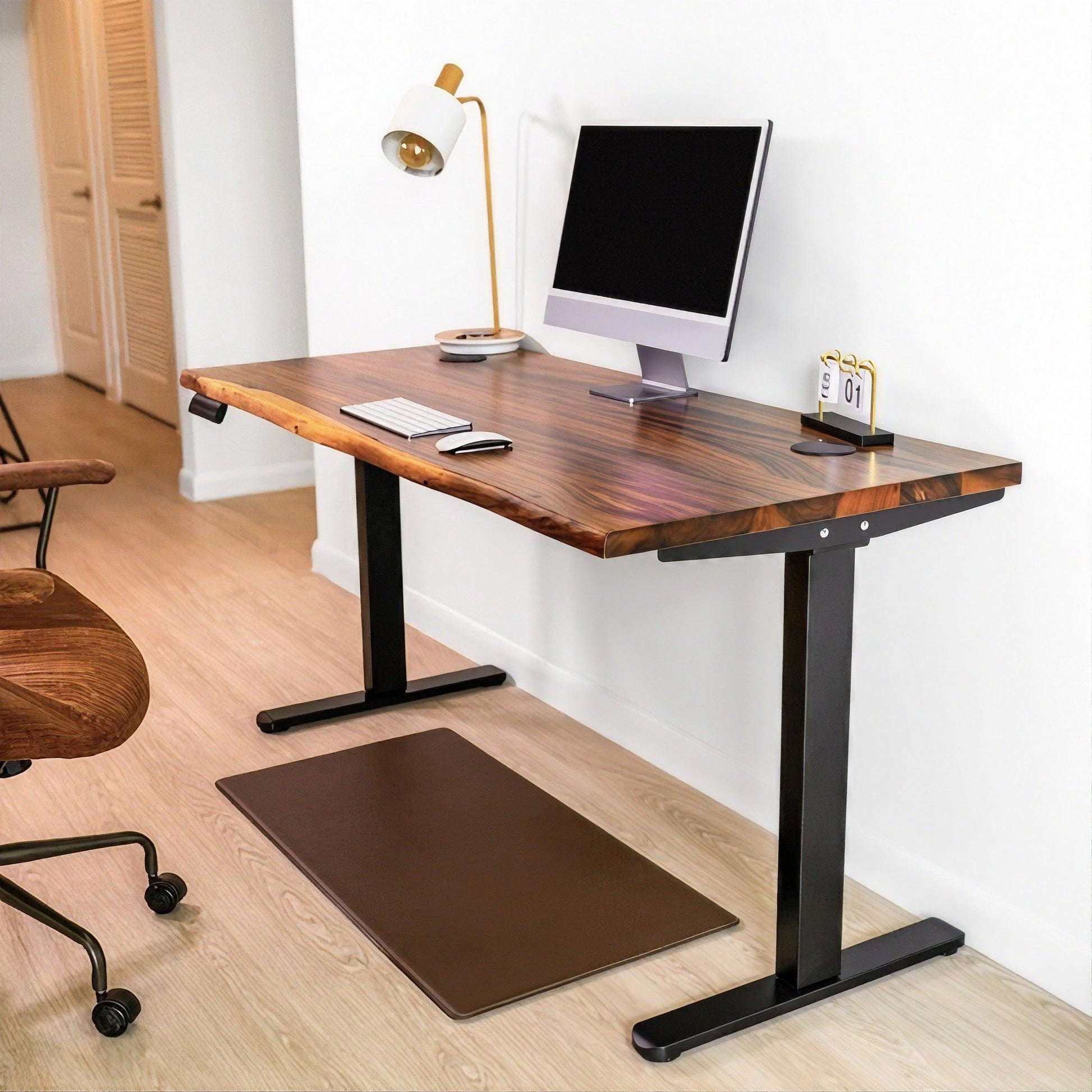 Modern minimalist home office with a sleek standing desk, complemented by a stylish gold lamp and ergonomic mat, creating a productive workspace.